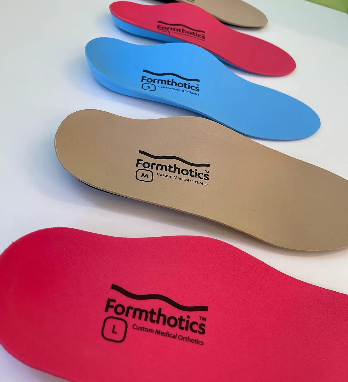 Orthotic insoles by Formthotics. Red, brown and blue insole options are shown