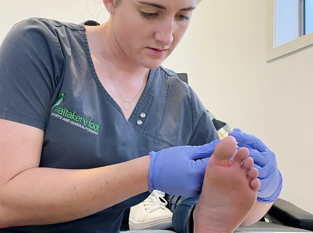 A podiatrist works on a patient's big toe.